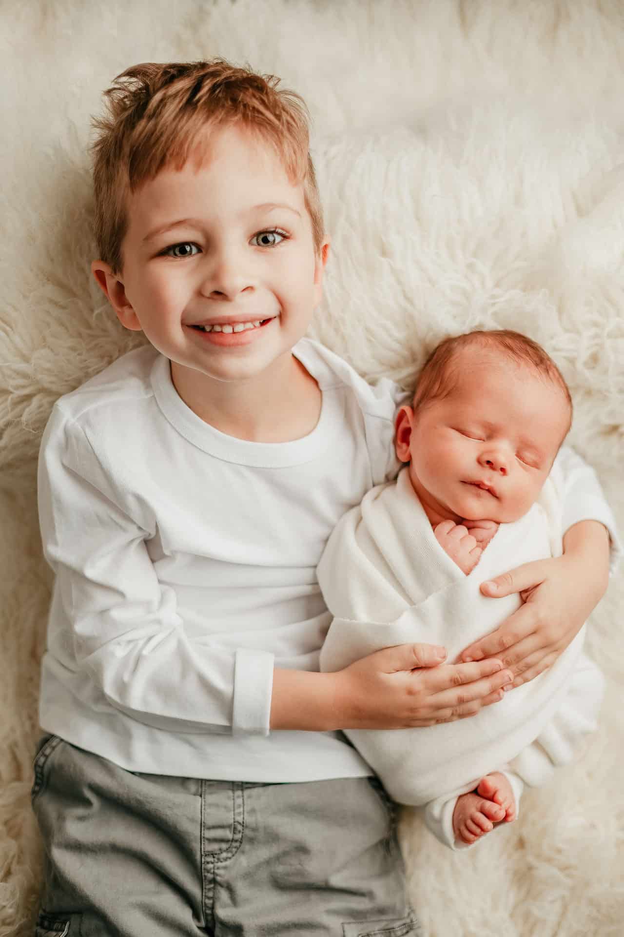 Big brother proudly holding newborn baby brother