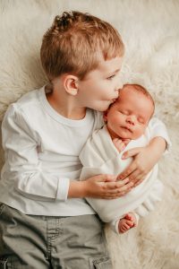 big brother kissing newborn baby