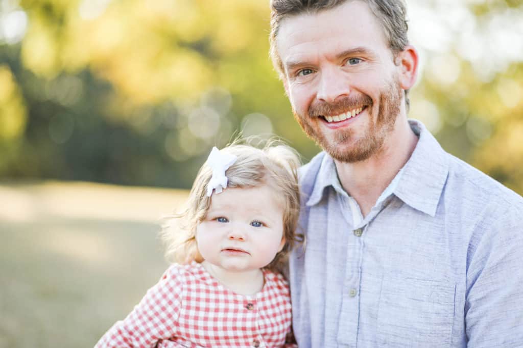 6 month old baby girl in plaid with dad in blue shirt smiling at camera