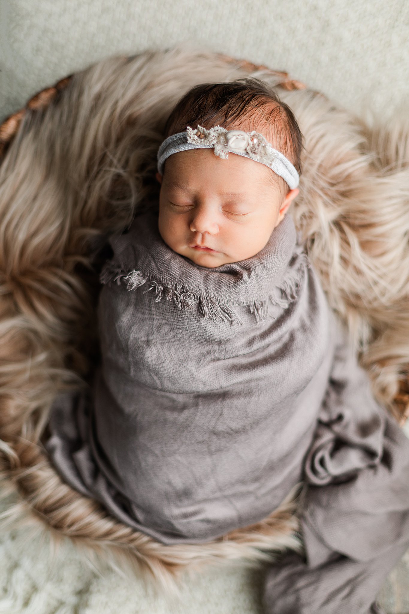 Baby swaddled in grey blanket sleeps in a fur blanket bed Nashville birth centers