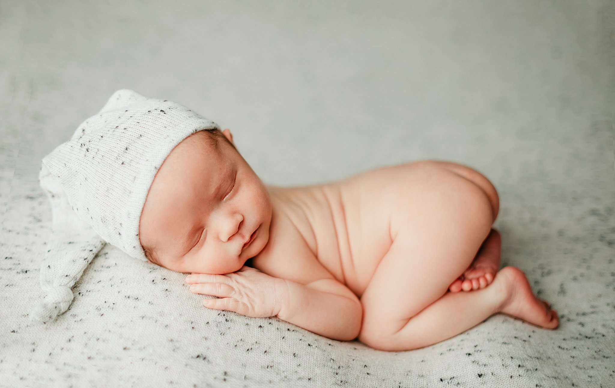 baby sleeps in froggy pose wearing a nightcap Nashville birth centers