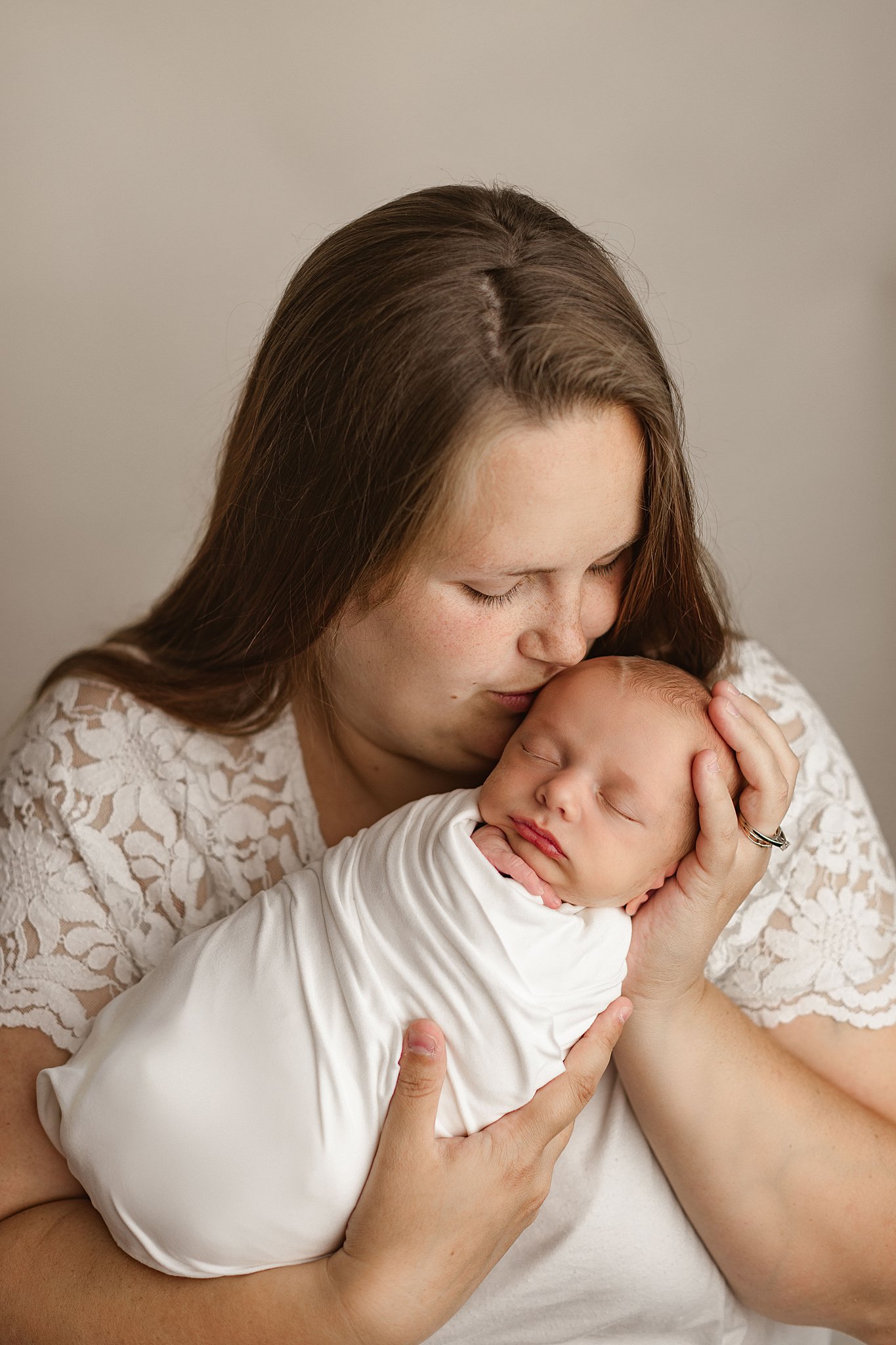 Mom kisses her newborn on the head in a studio nashville daycare