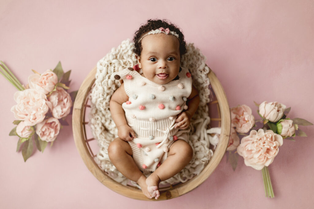 6 month baby girl posed in basket on pink in amanda barrett photography studio